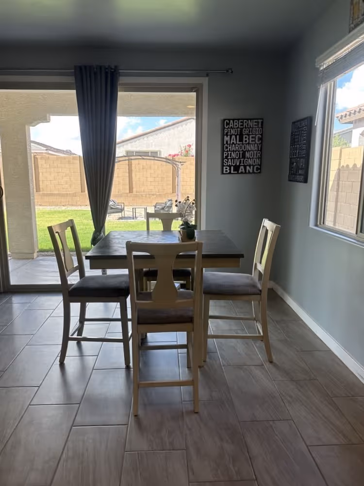 Dining room with wooden table and four chairs near sliding glass door to backyard.
