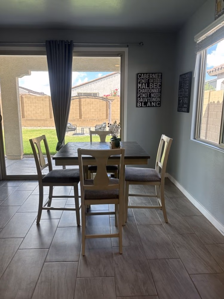Dining room with wooden table and four chairs near sliding glass door to backyard.